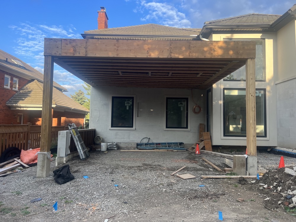Covered patio pergola framing over stucco house