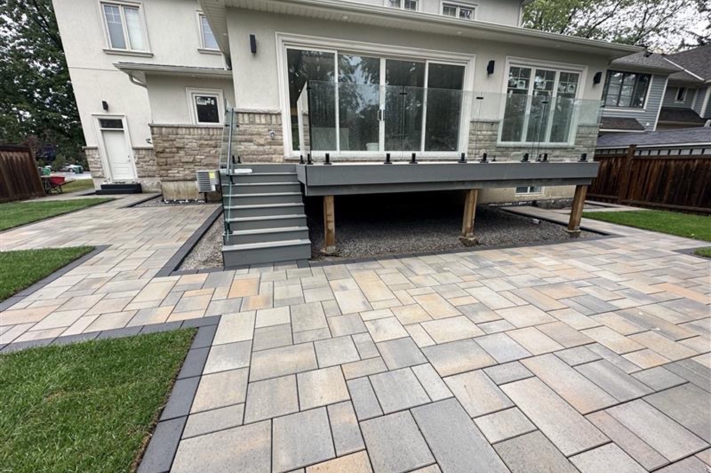 Finished paved patio with glass railing deck